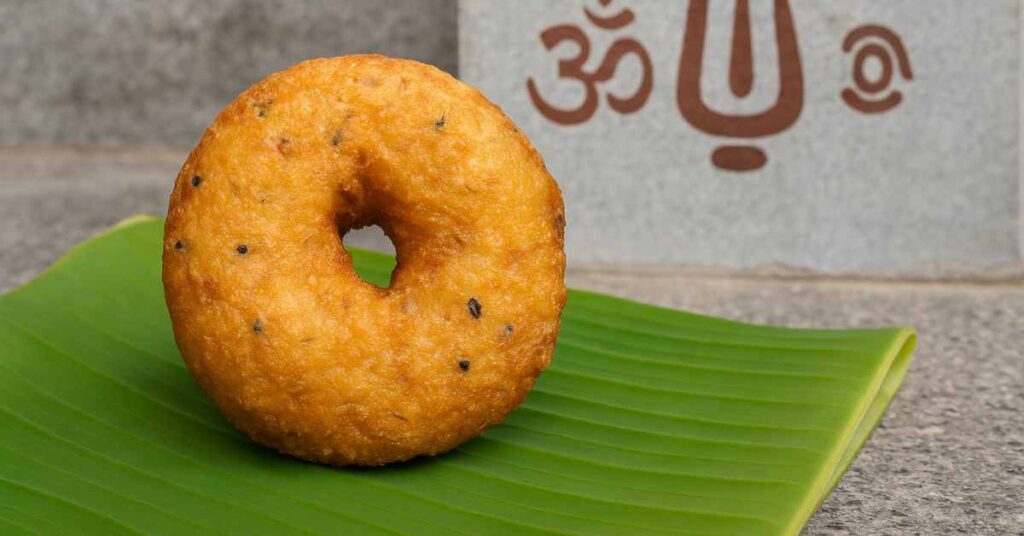 Tirumala Vada Prasadam placed on a banana leaf with devotional backdrop